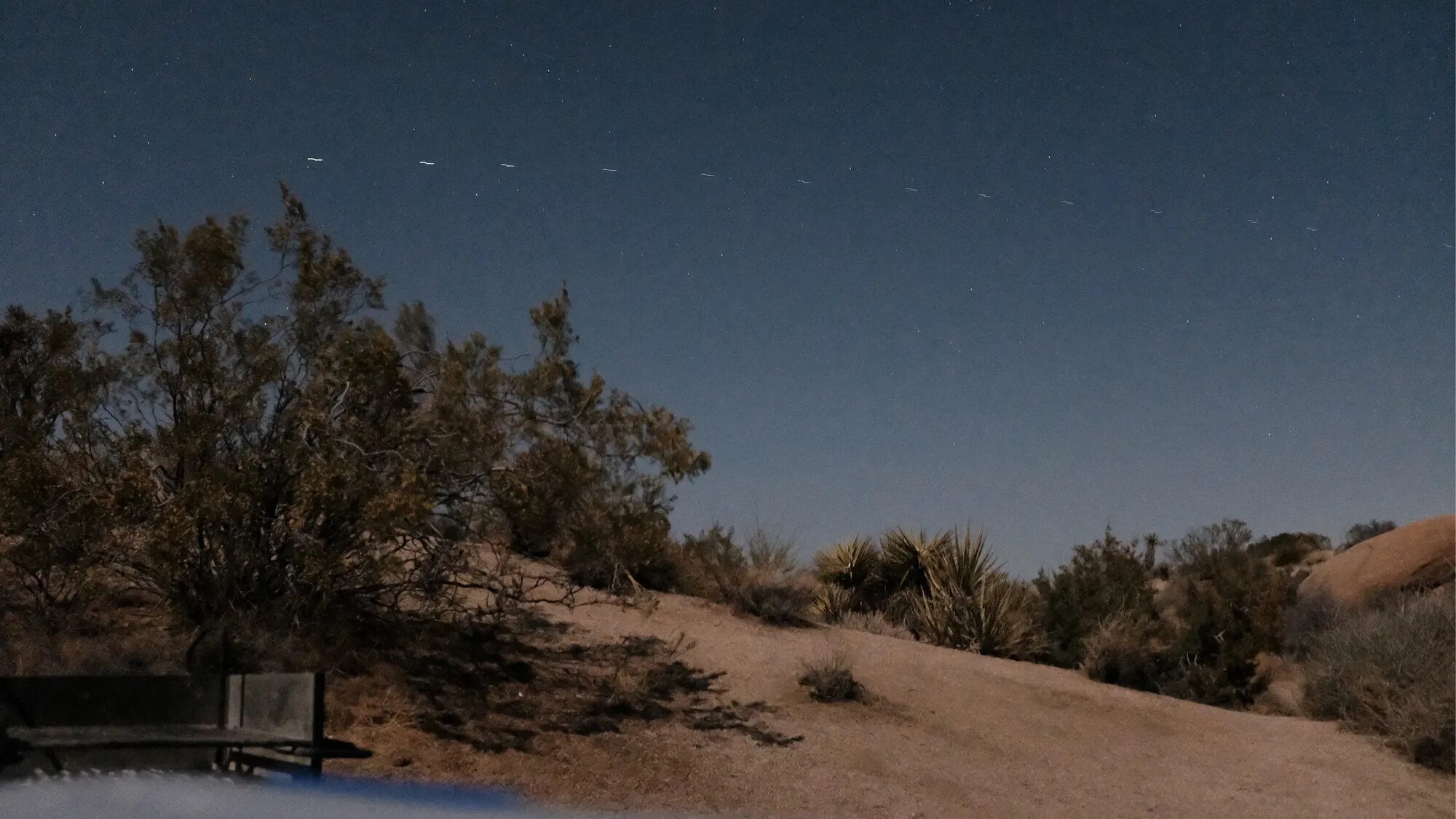 Long-exposure of the night sky over Joshua Tree, a line of Starlink satellites crossing it